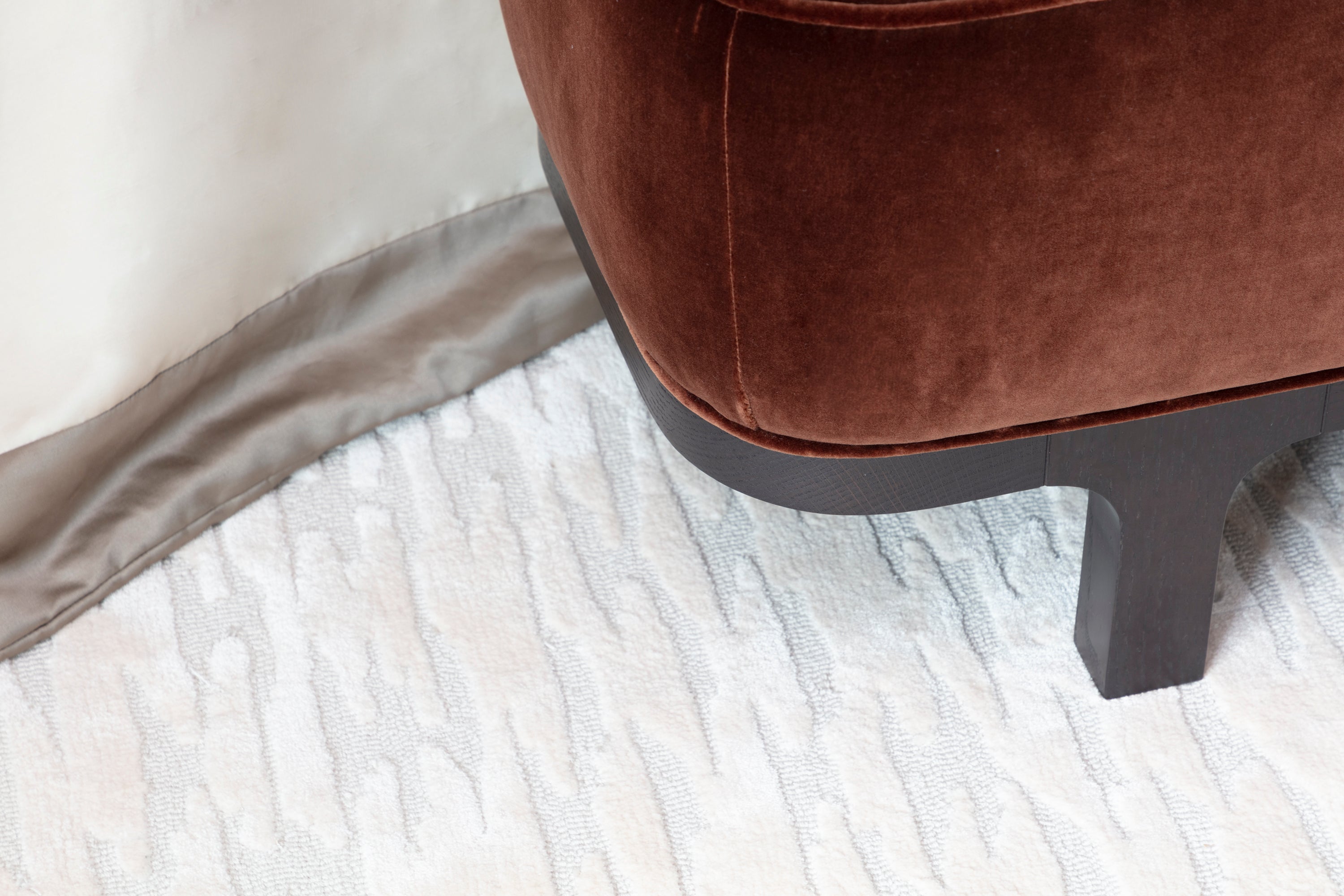 Chocolate bed footer with handmade rug and luxury throw selected by Nineteen Interiors.