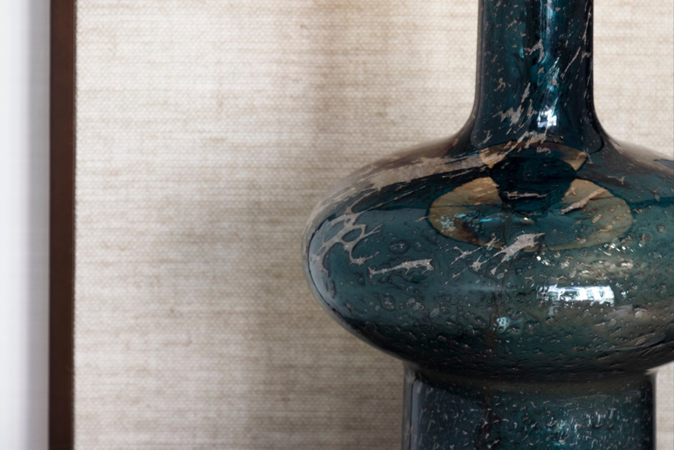 Close-up of a dark blue ceramic vase with a textured surface against a neutral background