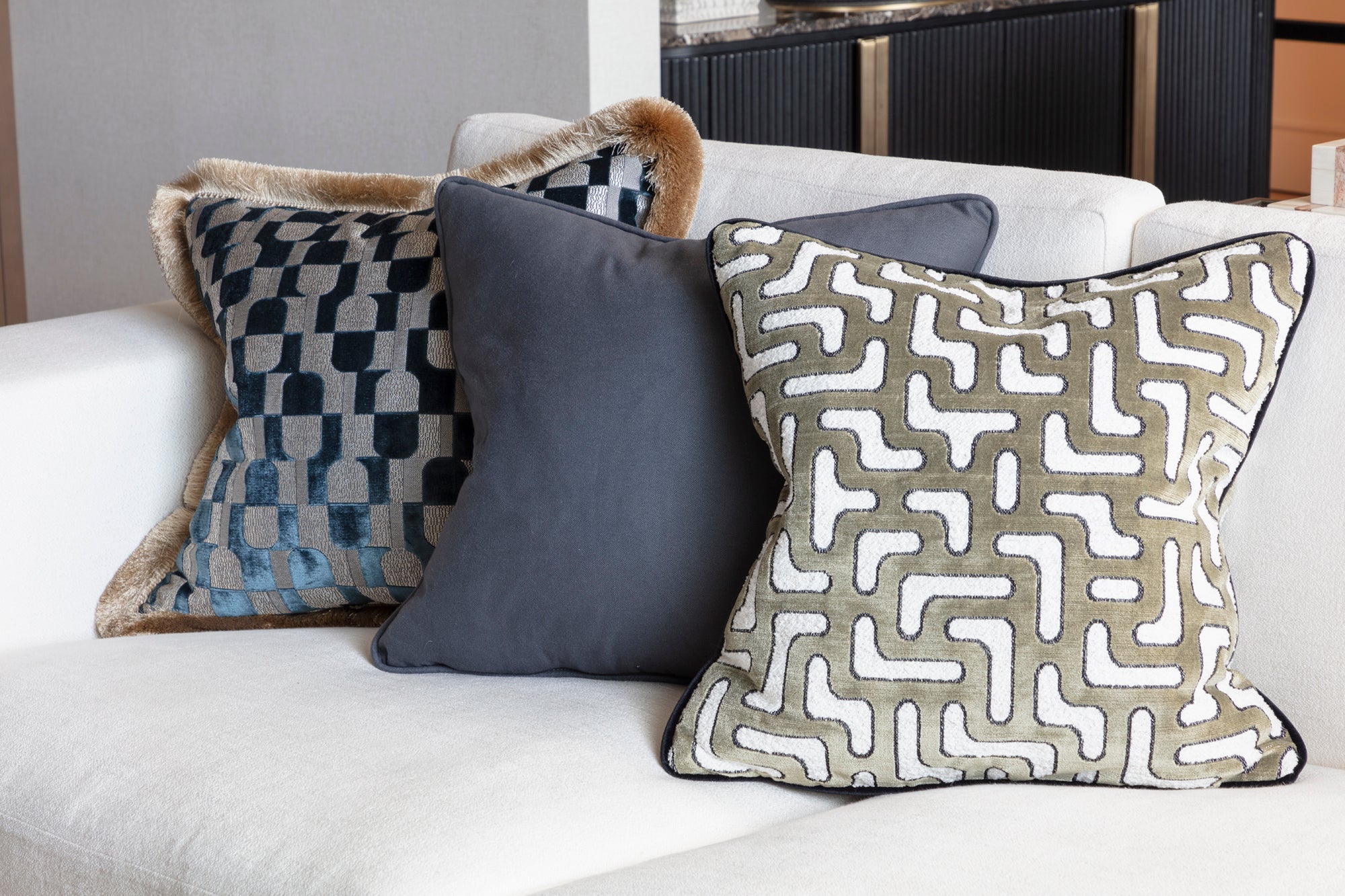 Handmade patterned cushions on a white bespoke sofa within a luxury apartment in Kensington, London by Nineteen Interiors and Alex Brown. 
