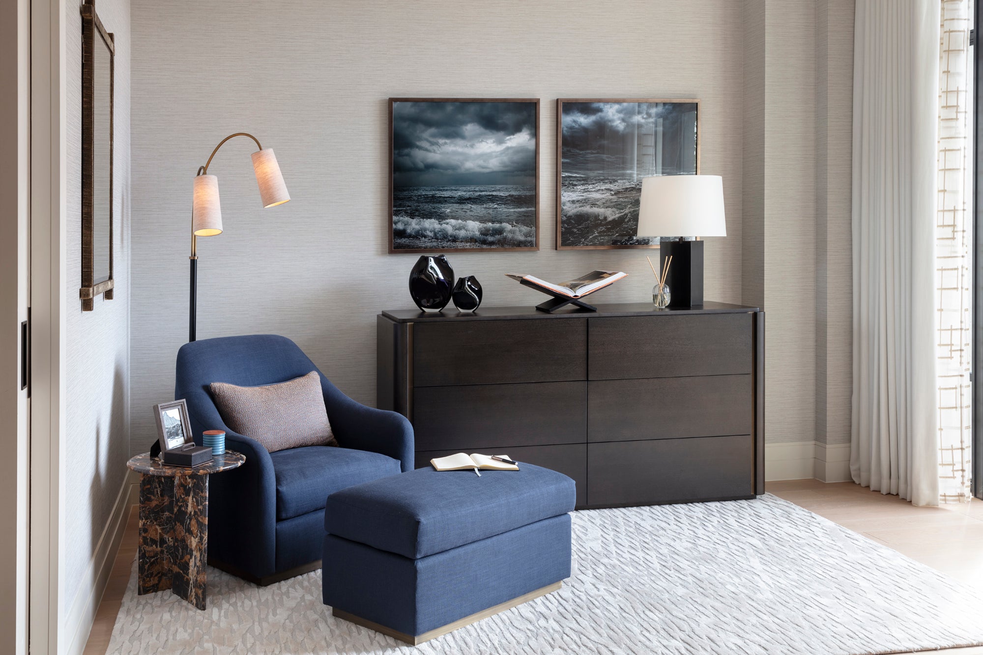 Master bedroom chill out space with bespoke lighting, blue armchair and bench, wooden sideboard, marble coffee table, custom framed artwork and Lutron curtains.