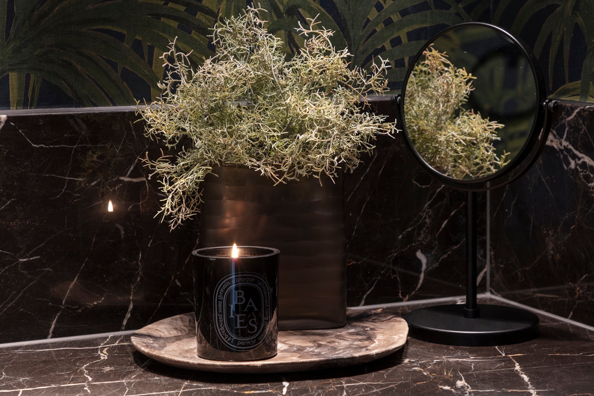 Luxury candle, marble worktop and jungle wallpaper in Kensington apartment.