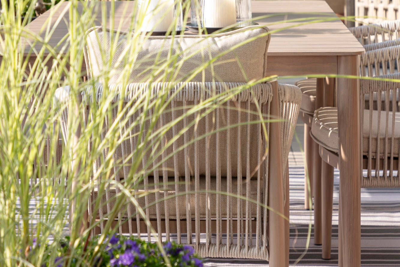 Outdoor furniture set with a table and chairs on a patio, surrounded by plants.