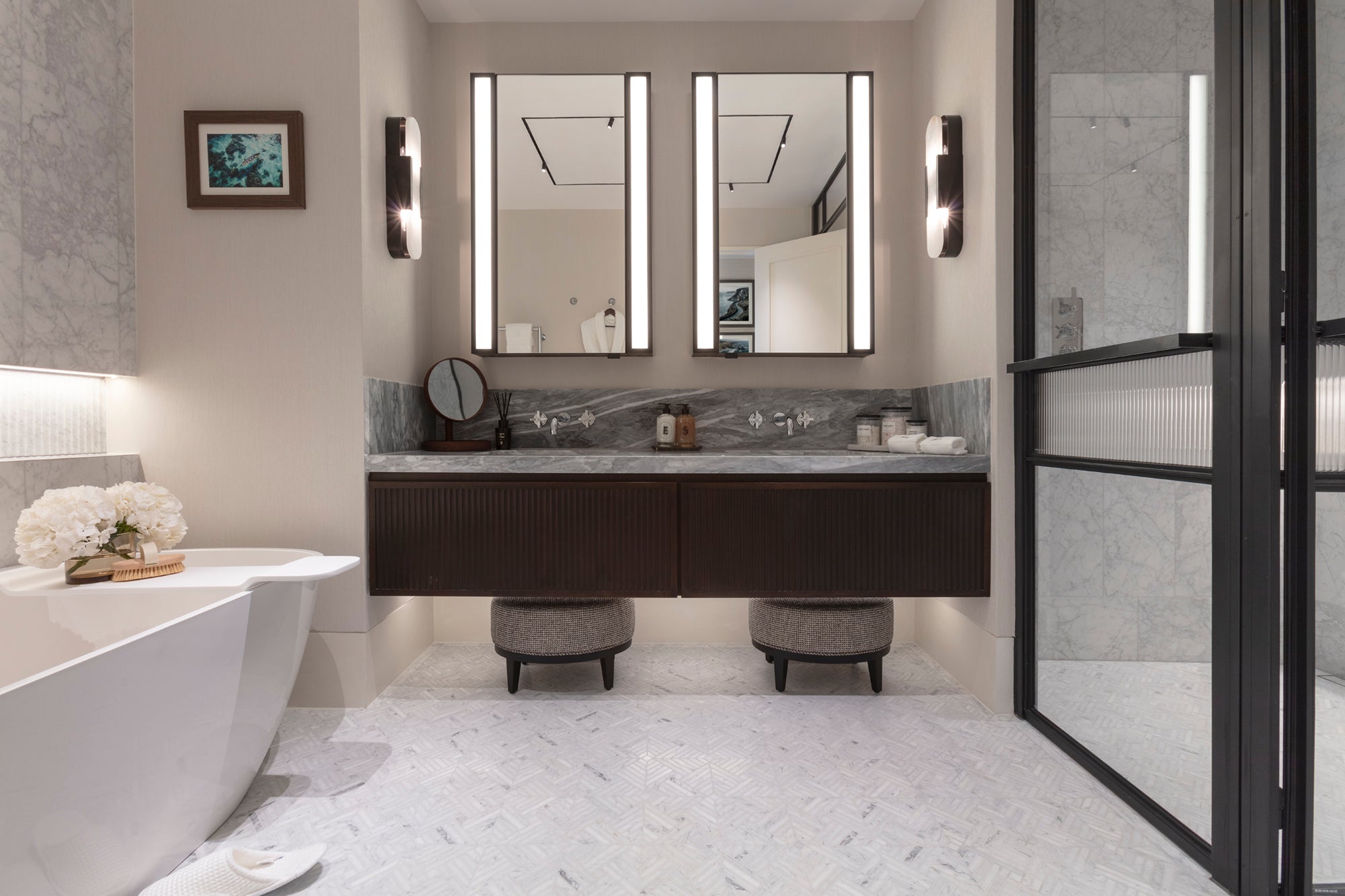 Modern bathroom with marble splashback, timber drawers, stone flooring and backlit twin mirrors. Styled by Nineteen Interiors.