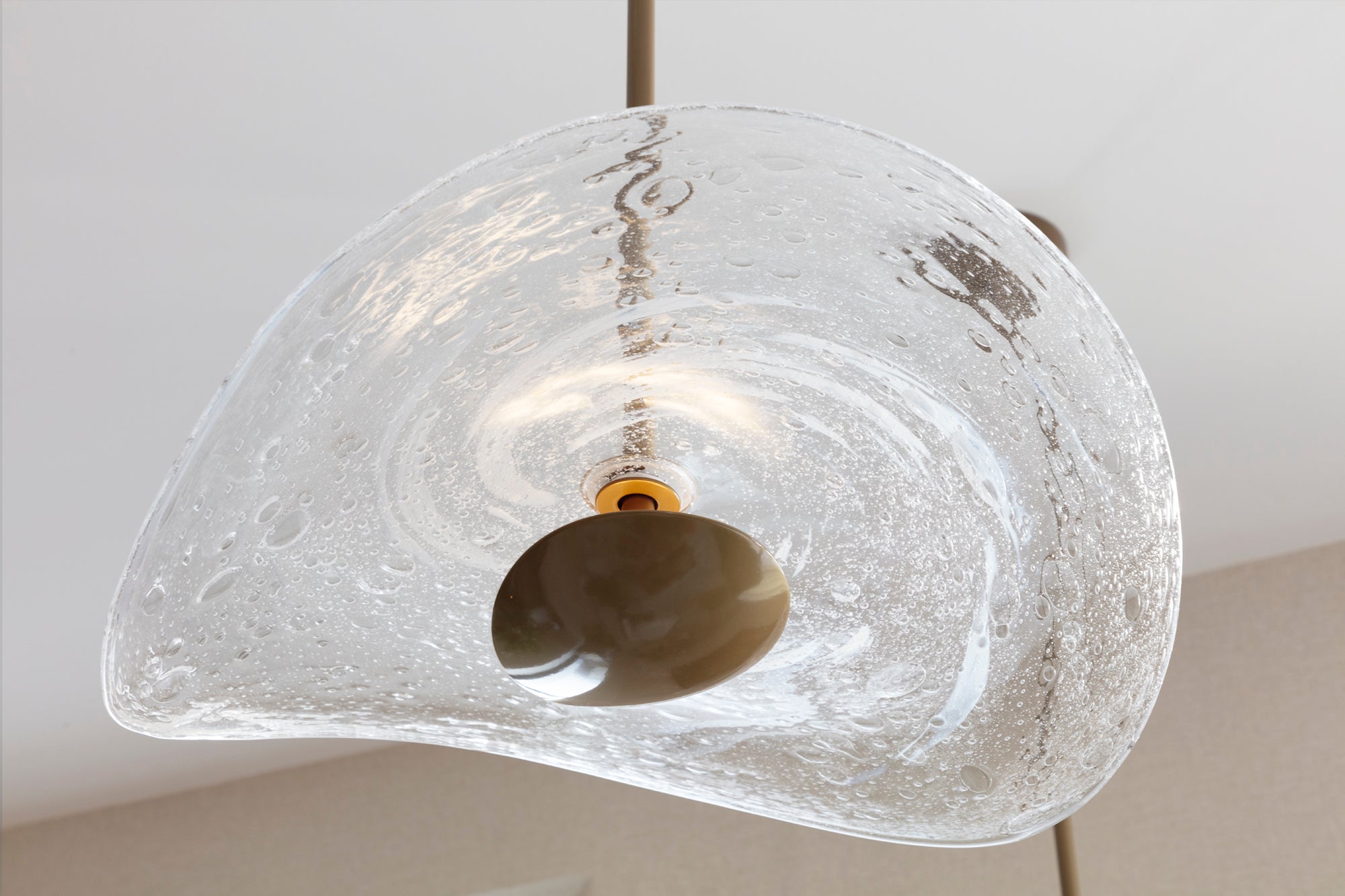 Modern pendant light with a glass shade and metallic fixture on a neutral background