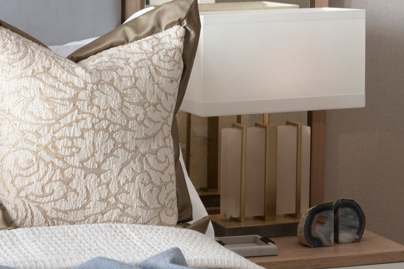 Luxury guest bedroom in netural tones with mottled mirrors, crystal lamps, textured handmade taupe cushions with gold trim and bespoke bedding.