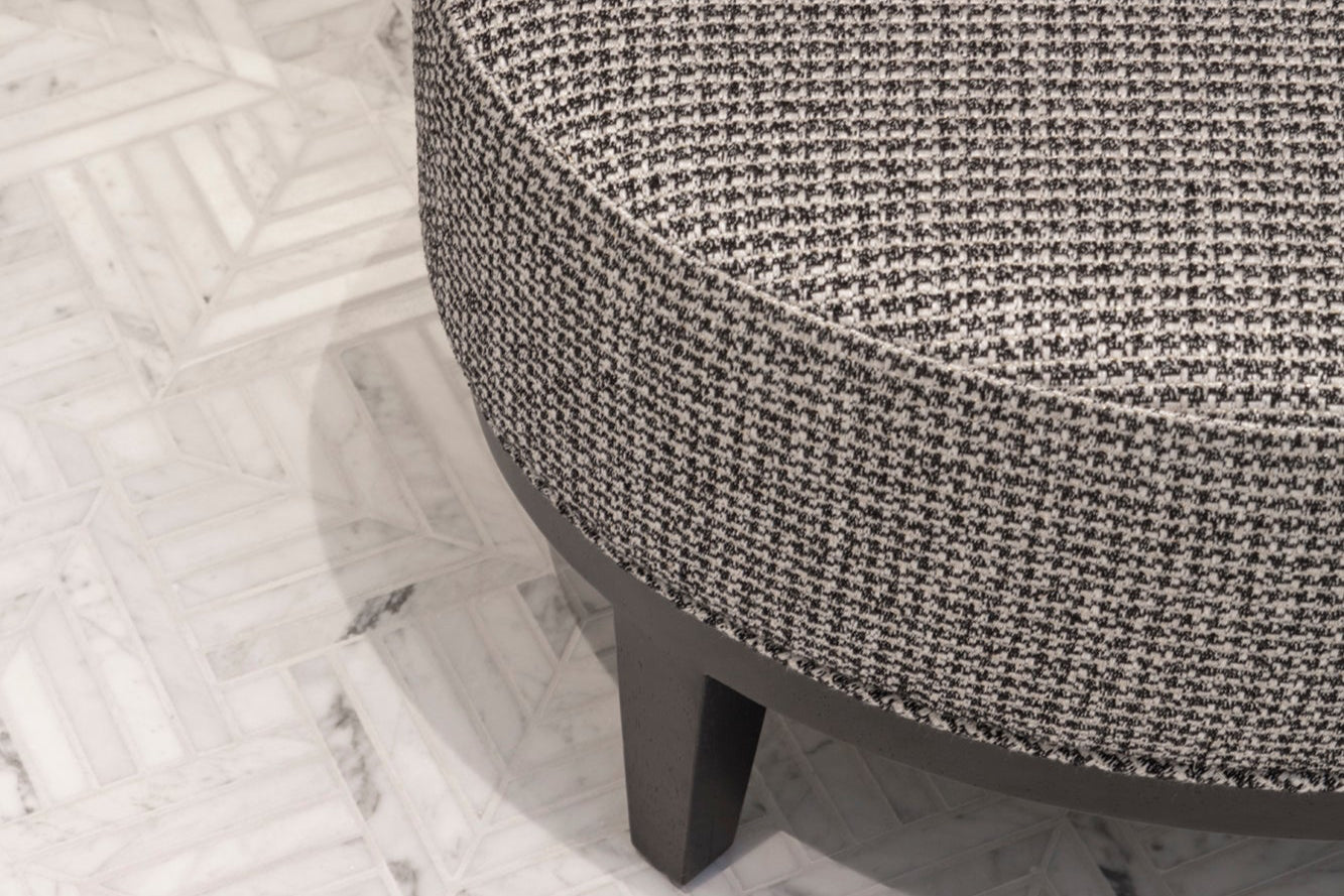 Round textured fabric stool in luxury modern masculine en-suite and patterened stone tiled flooring.