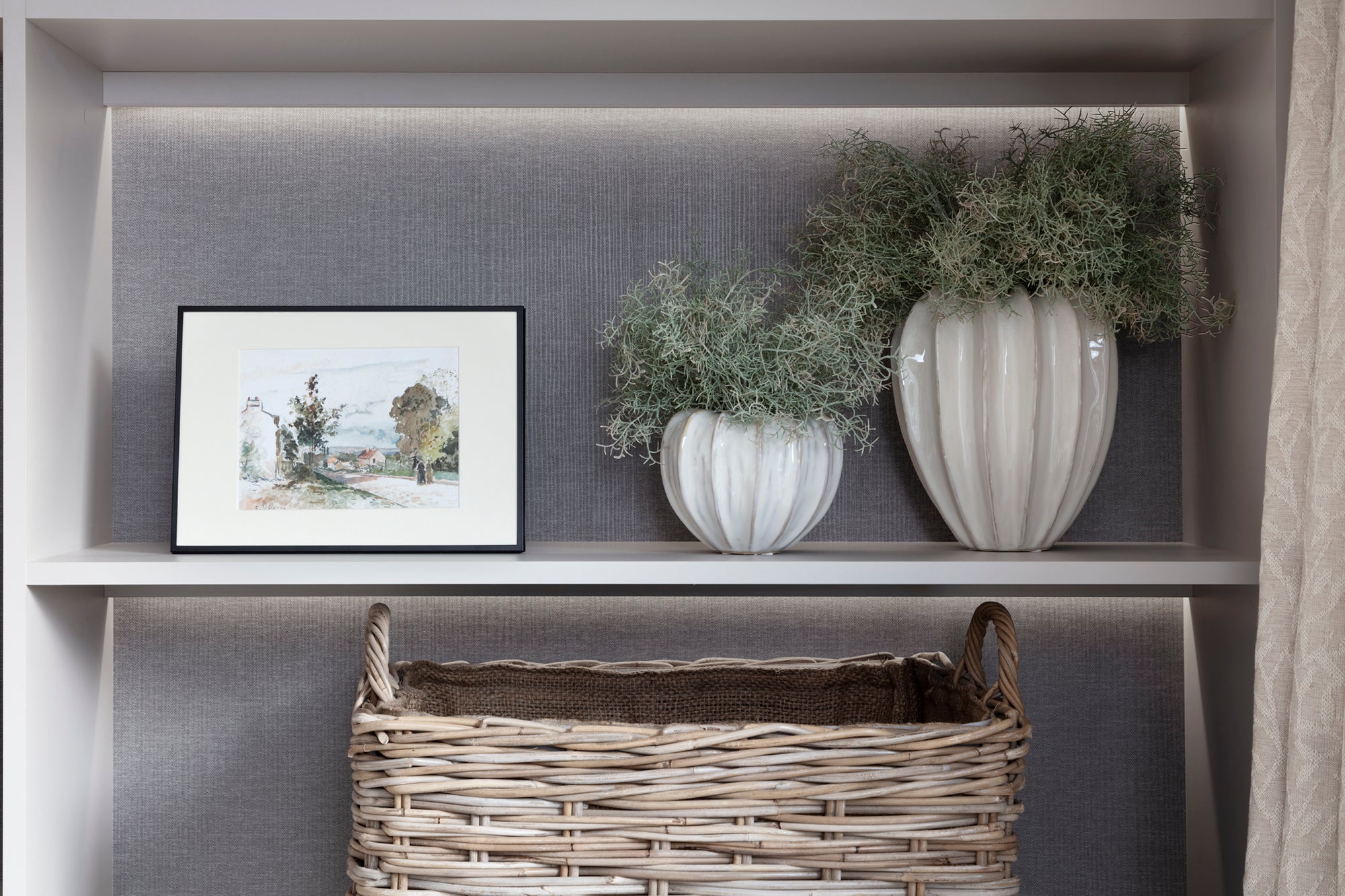Bespoke joinery media wall with feature lighting, surrounded by carefully selected interior design and home accessories, including a stone vase with flowers. The design creates a stylish and sophisticated space with thoughtful details for a modern home