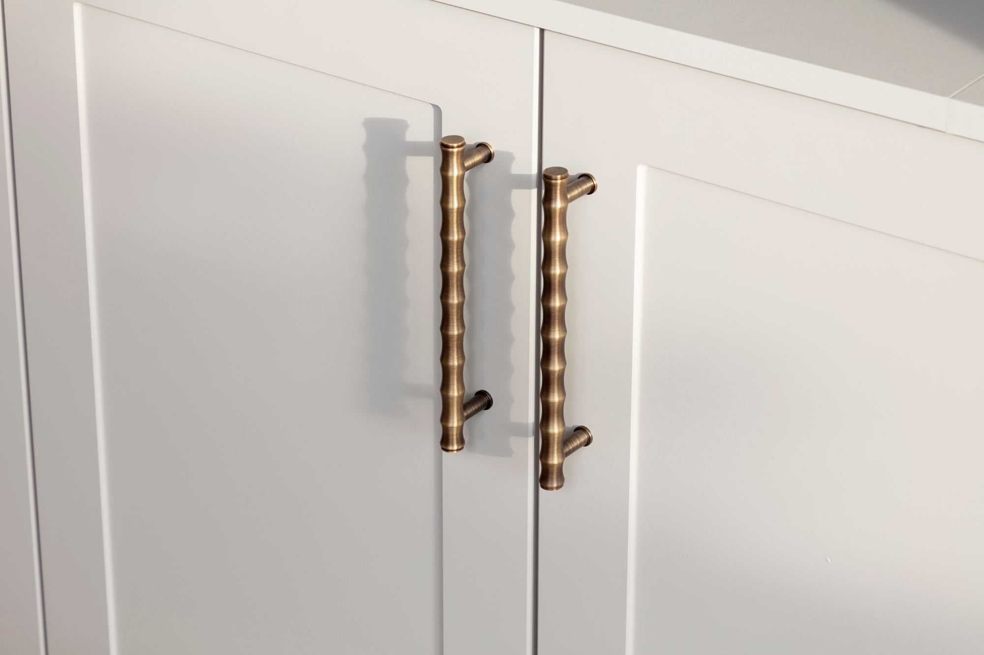 Custom ironmongery and bespoke joinery unit in a family lounge featuring a built-in TV and speakers. The painted unit and stylish wallpaper enhance the space, creating a modern and functional living room design with thoughtful details