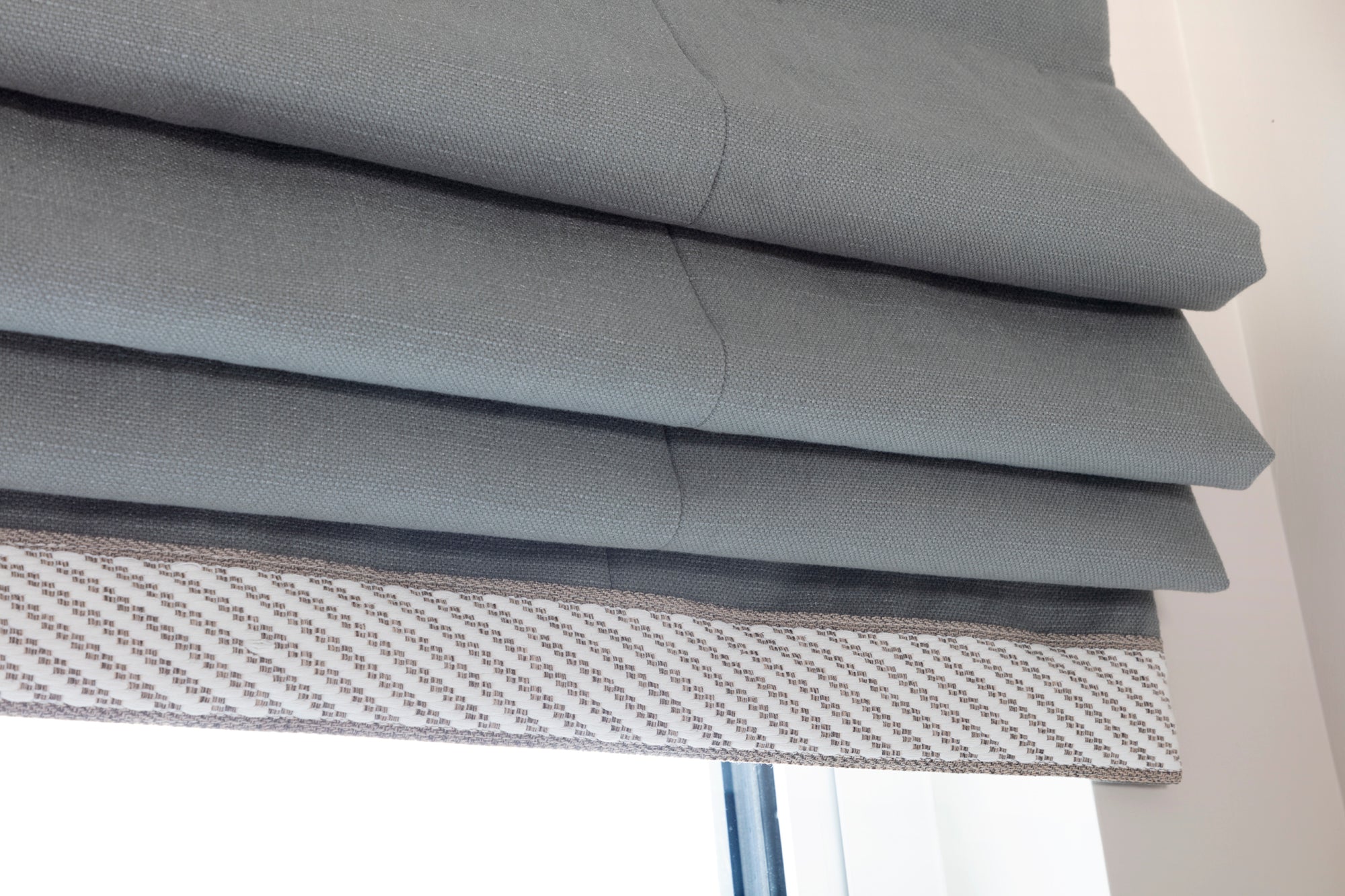 Custom-made roller blinds with decorative trim and precise window finishes, hand-measured by an interior designer. The luxury products enhance the space with tailored, high-quality design, offering both elegance and functionality in every detail