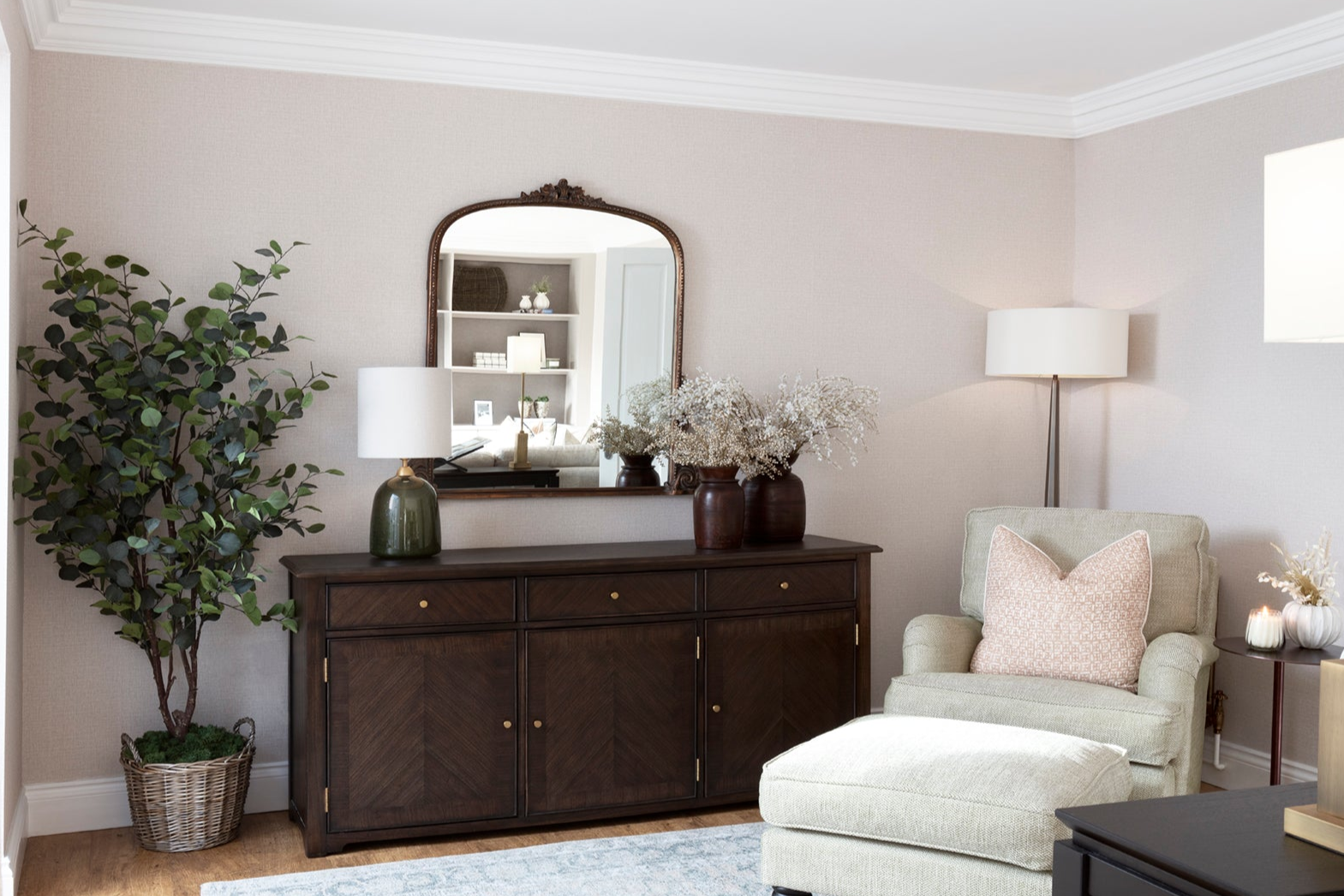 French-inspired reading area with armchair, timber bespoke joinery elements, handmade glass lamp, and greenery in basket weave. Neutral tones, calming wallpaper, and detailed coving and skirting create a serene and sophisticated atmosphere
